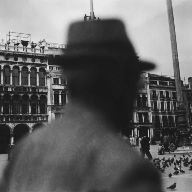 Un homme portant un chapeau se tenant face à un immeuble.